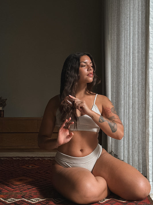 Woman sitting on a rug indoors, wearing a white bra and underwear Cotton Set Love Child Bali.